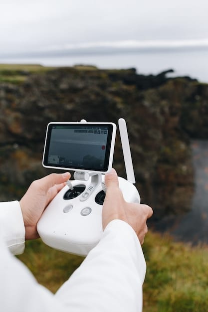 A person holding a drone remote controller, with the FAA DroneZone website displayed on a laptop in the background.