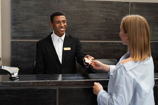 A person standing at a hotel concierge desk, smiling and holding a room key, indicating an upgraded room benefit from their elite status in a hotel loyalty program. The concierge is smiling encouragingly.
