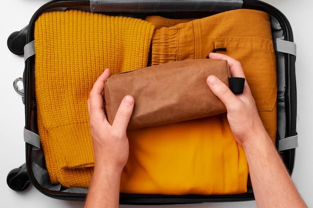 A traveler's hands carefully folding clothes inside a carry-on suitcase, demonstrating the rolling technique. Other items are neatly arranged around, showing a systematic approach to packing.
