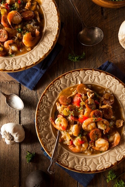 A close-up shot of a plate of steaming hot New Orleans gumbo, showcasing the rich, dark roux, chunks of andouille sausage, shrimp, and okra. It looks incredibly flavorful and authentic.