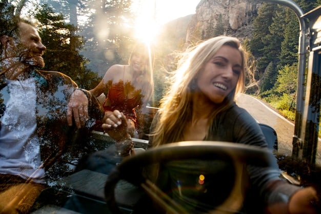 A couple laughing together in the front seats of a car, with a scenic view of a national park visible through the windshield. They each have headphones on and are enjoying a podcast or audiobook.