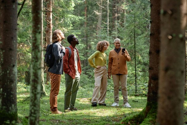 A group of tourists participating in a guided nature walk in a US forest, led by a park ranger. The focus is on educational and eco-friendly tourism.