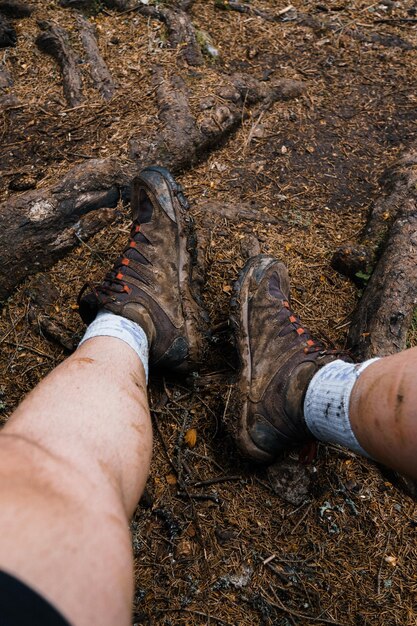 A close-up shot of a hiker's boots on a muddy trail in the US. The hiker is using gaiters to protect their boots and prevent mud from entering. The image emphasizes the importance of protecting trails from mud and water damage.