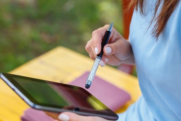 A person designing a digital product (e-book cover) on a tablet with a stylus, with travel photos and design elements scattered around. The image highlights the creative process of developing digital products for travel blogging.