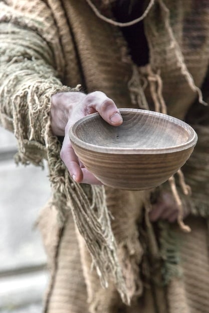 A close-up shot of a weathered hand holding a traditional craft item, with a blurred background showing a local artisan at work. The image conveys a sense of cultural authenticity and the human connection behind the creation of handmade goods.