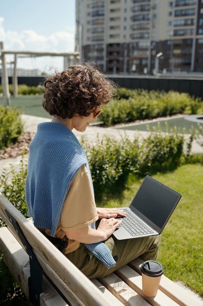 A person working on a laptop at an outdoor café, with a scenic cityscape in the background, blending work and leisure. The scene captures the 
