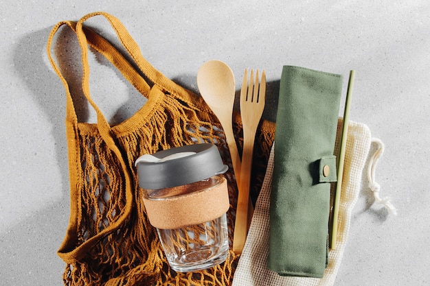 A close-up shot of a traveler packing a bamboo cutlery set, reusable food wraps, and a beeswax food wrap into a travel backpack, emphasizing the importance of bringing your own utensils to reduce single-use waste during travel.