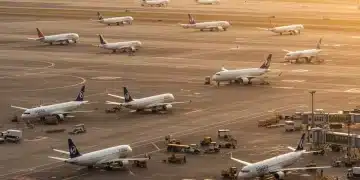 Busy US airport tarmac with airplanes and ground crew, symbolizing increased summer 2025 airline capacity.